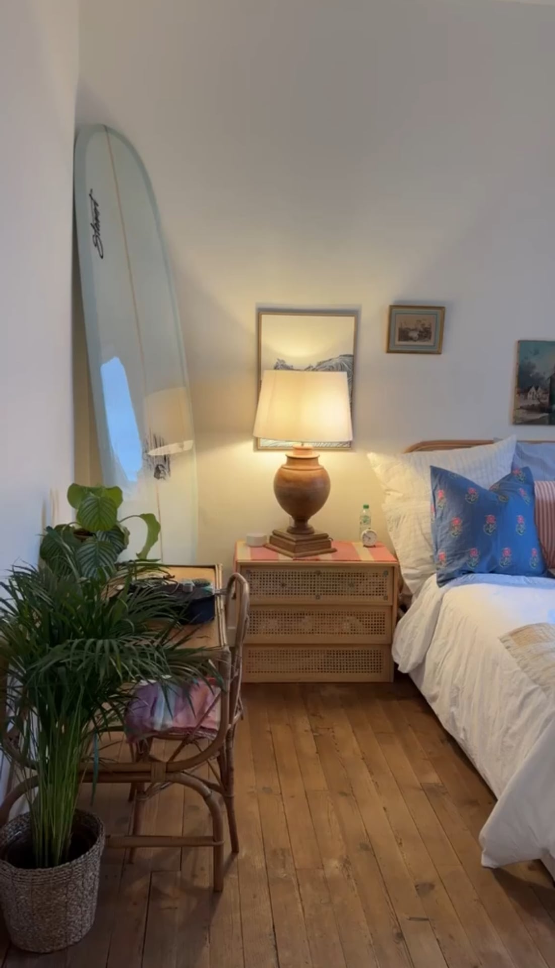 Second bedroom with a cane chest, framed prints and a surfboard against the wall