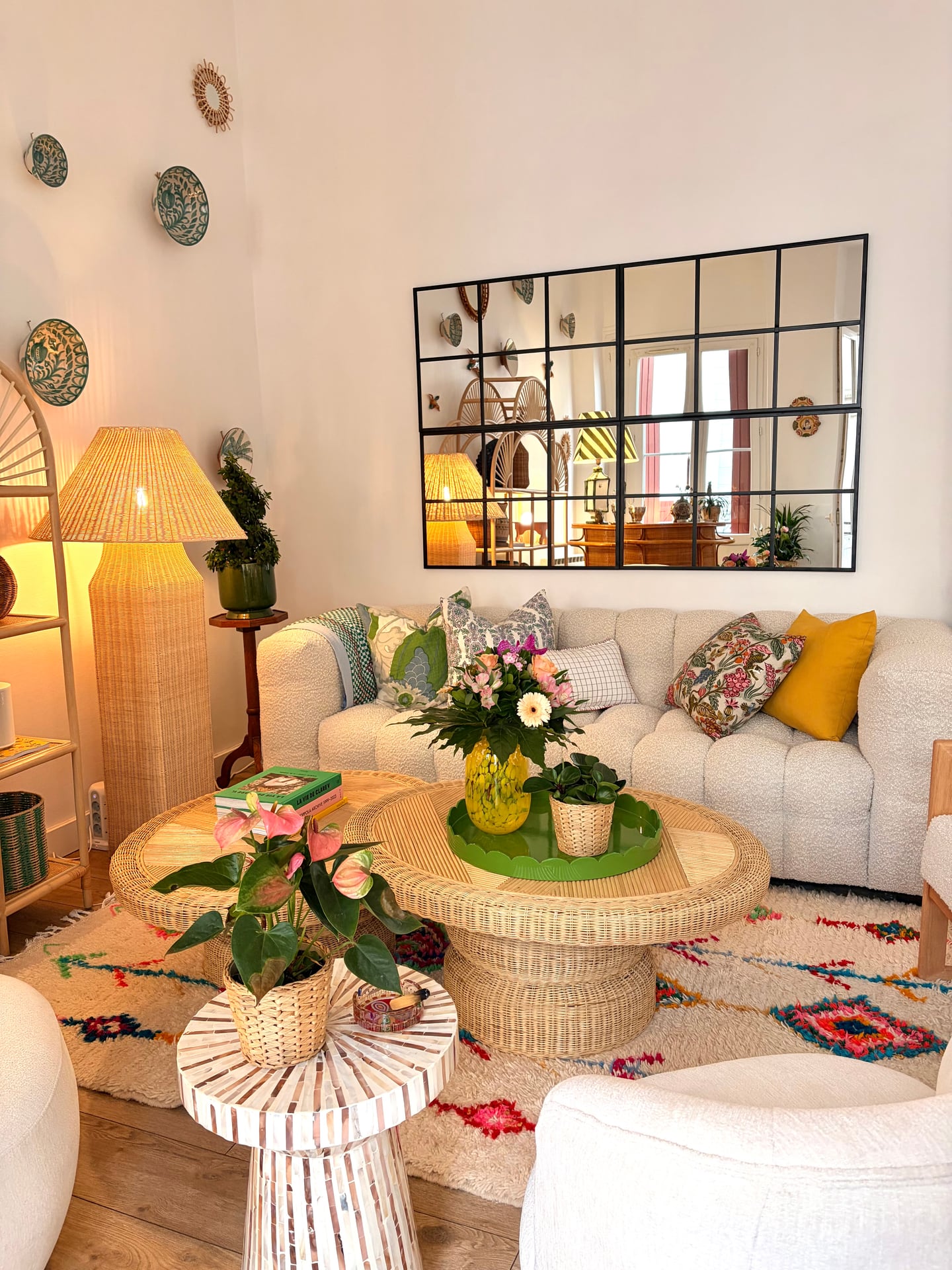 Soft sofa under the grid mirror with wicker coffee tables and flowers