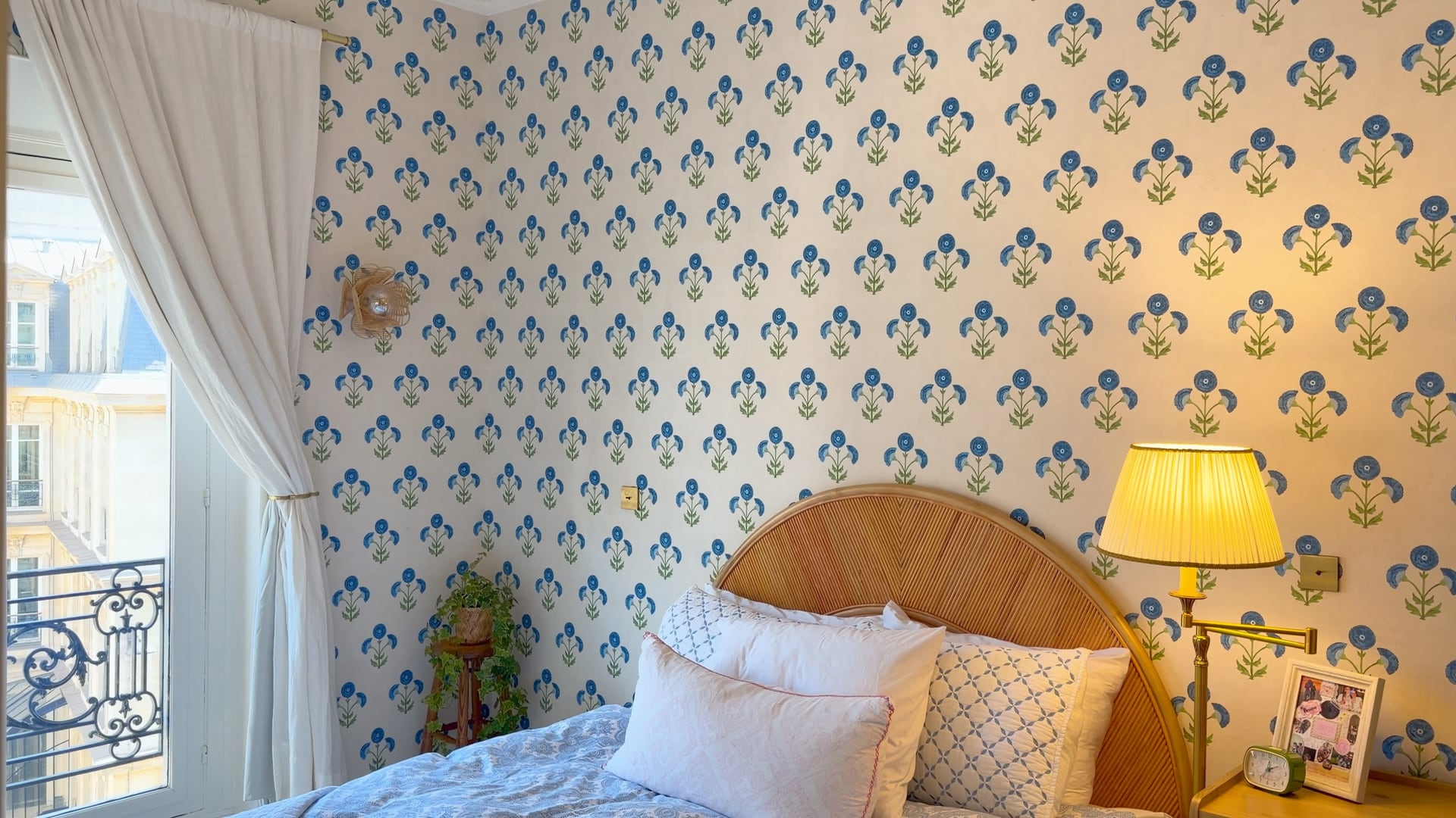 The rattan headboard and lamp against the blue floral wallpaper