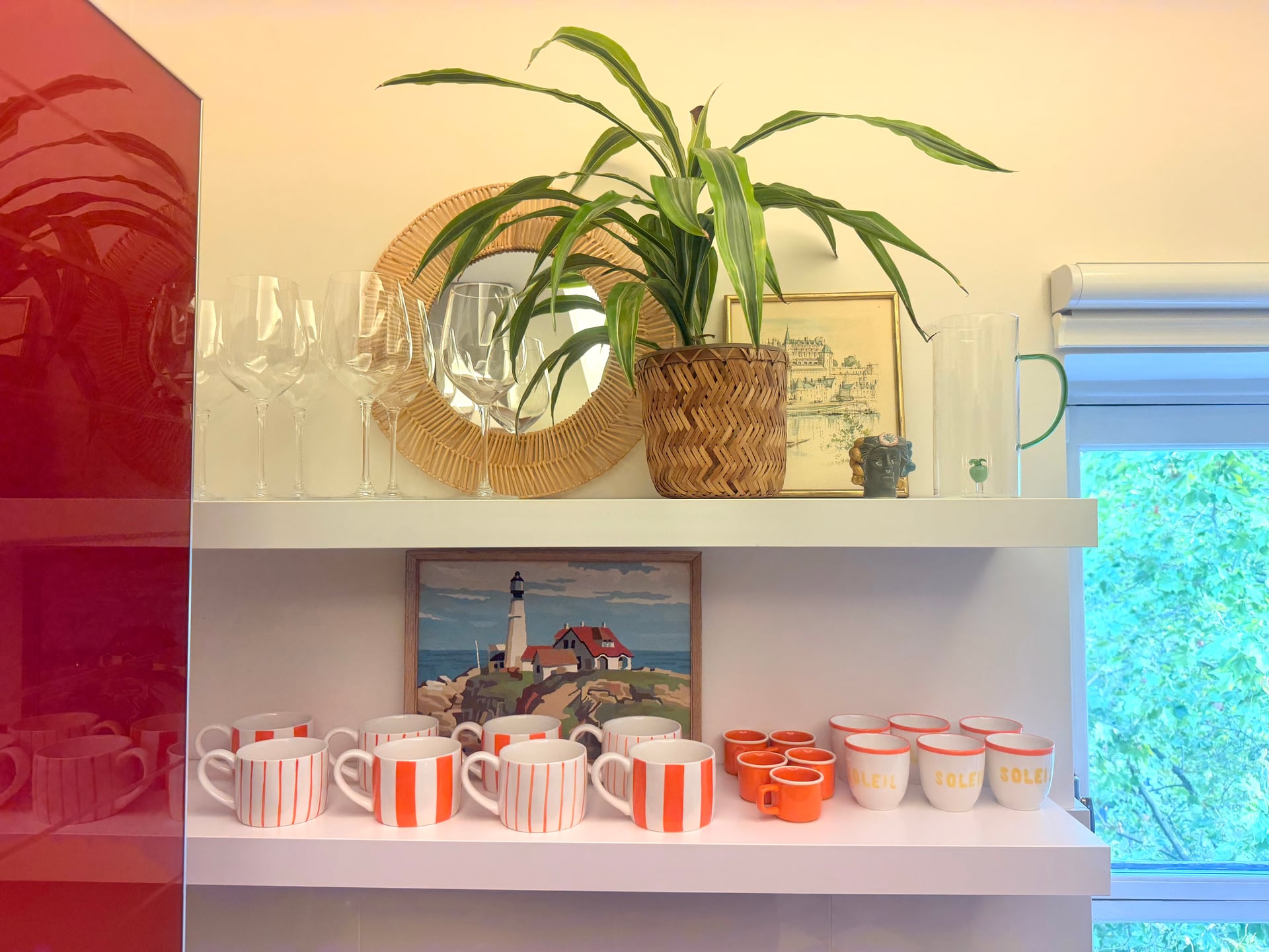 Open shelves with striped mugs by the window